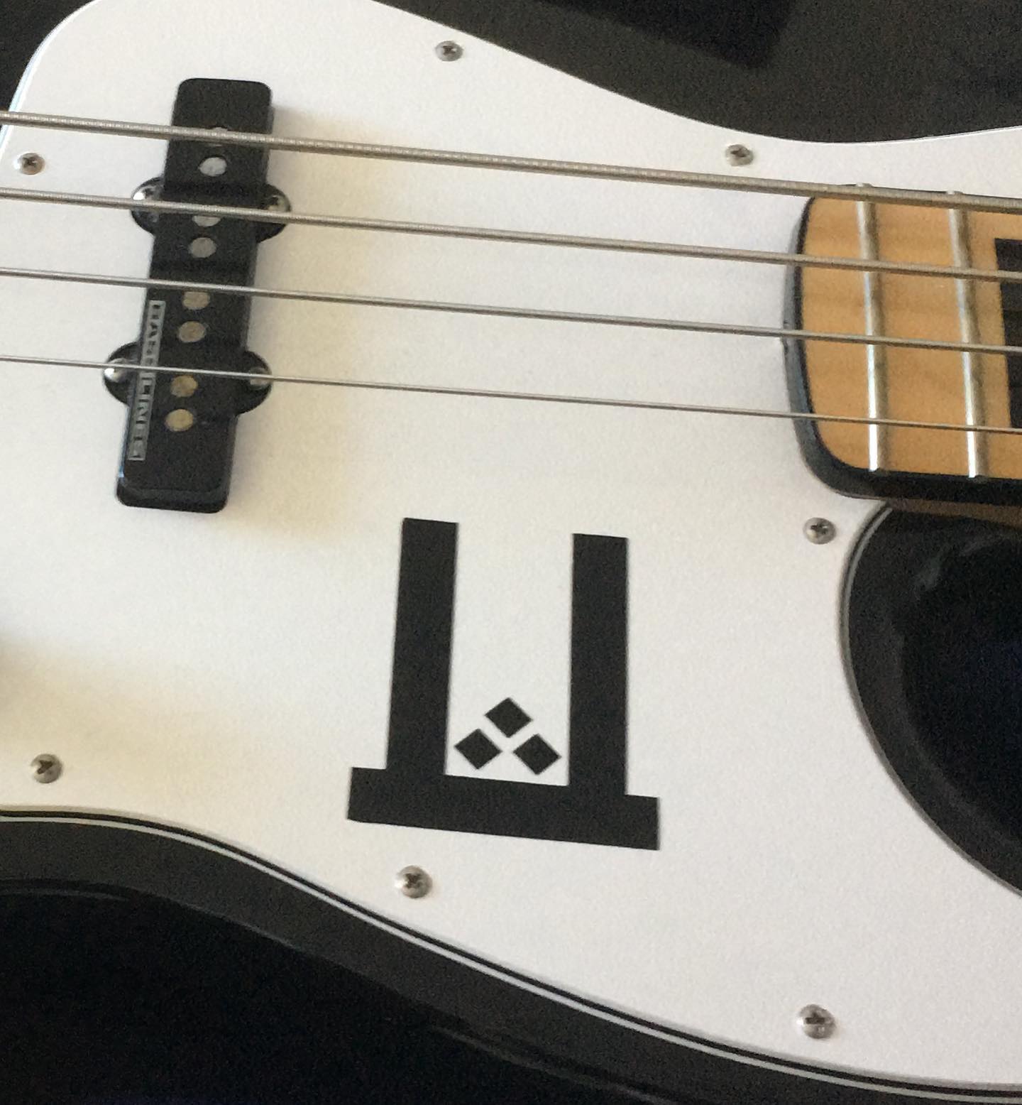 A close up of the Ritual Effect 'U' symbol decal on Christopher's bass guitar