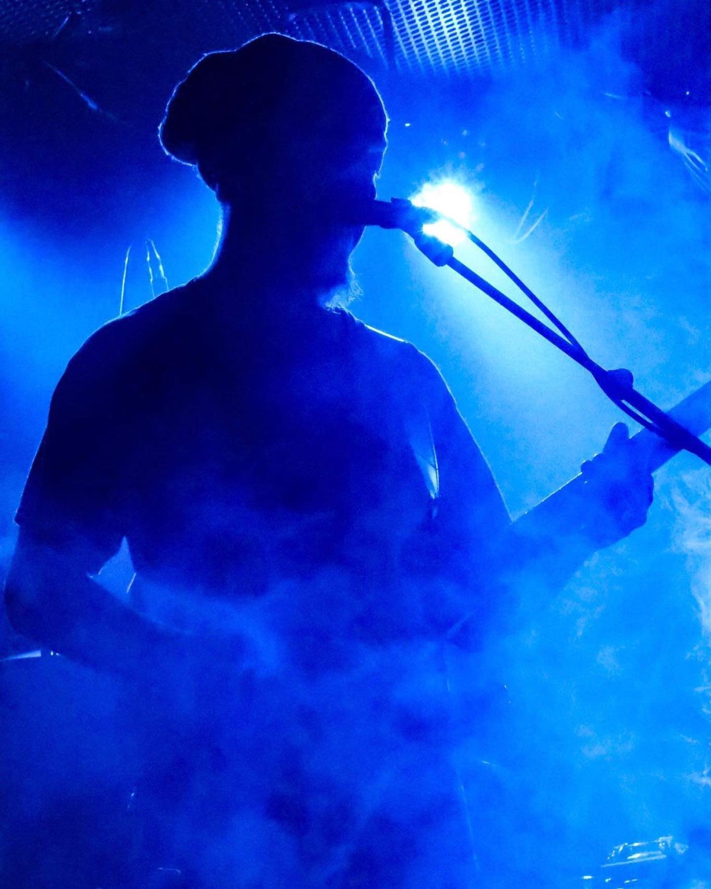 A blue-tinted silhouette of Moe live on stage