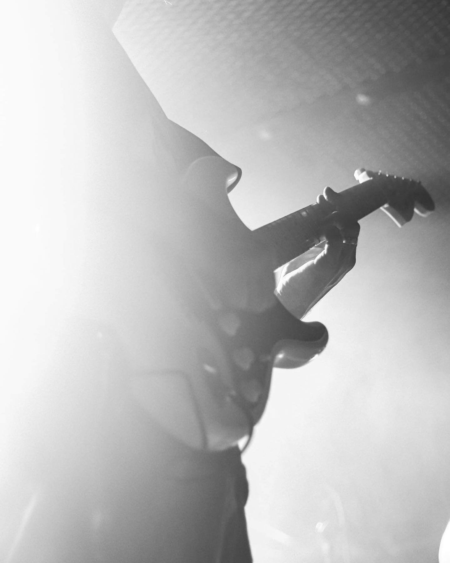 A black and white, misty image of Moe's stratocaster guitar being played live on stage